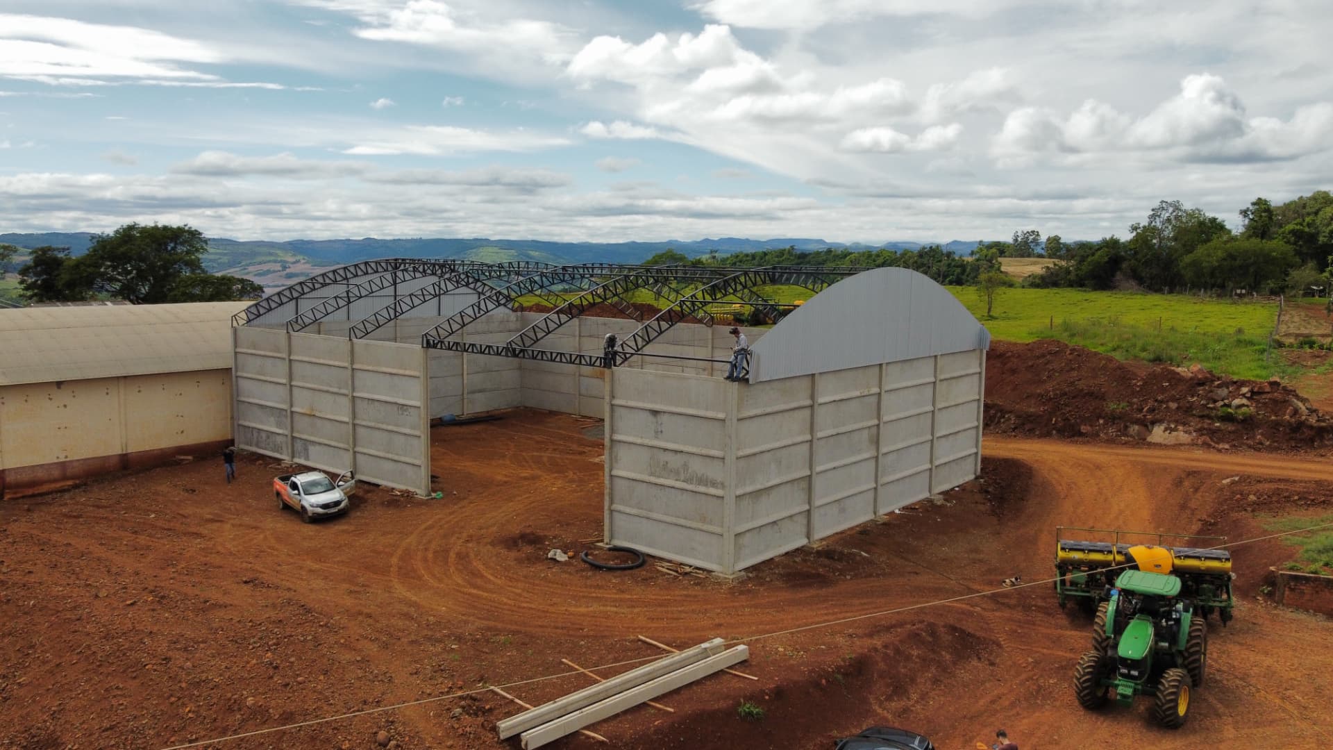 Barracão em construção com painéis de concreto e tesouras metálicas